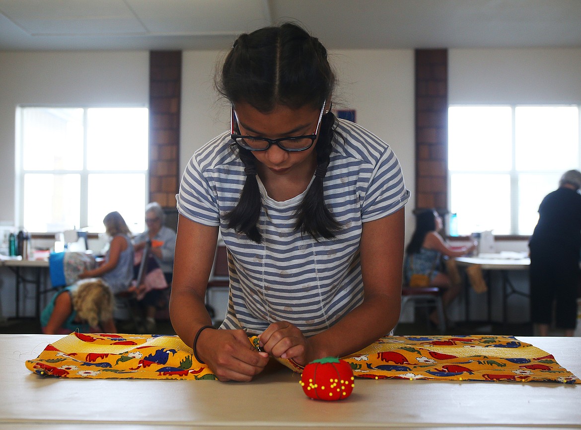 Mirra Elliott, 12, pins the drawstring for her backpack during the annual youth sewing and quilting camp Tuesday afternoon at the Coeur d'Alene Shrine Club Event Center in Hayden. (LOREN BENOIT/Press)