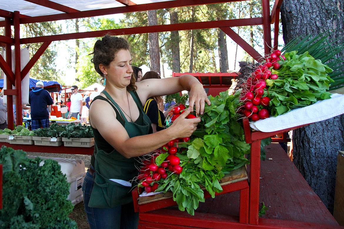 Kelsey Racicot, 29 of Bayview restocks radishes at the Rugged Roots Farm booth. Rugged Roots Farm specializes in ecologically grown produce, flowers and herbs. (Photo by Andreas Braunlich.)