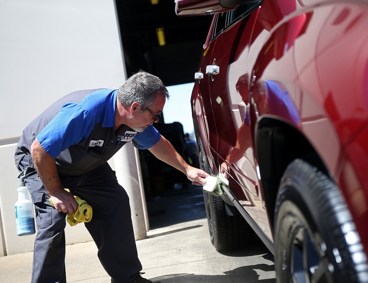 Head detailer Casey Latuseck cleans the bottom of a GMC Terrain at Mike White Ford in Coeur d&#146;Alene.