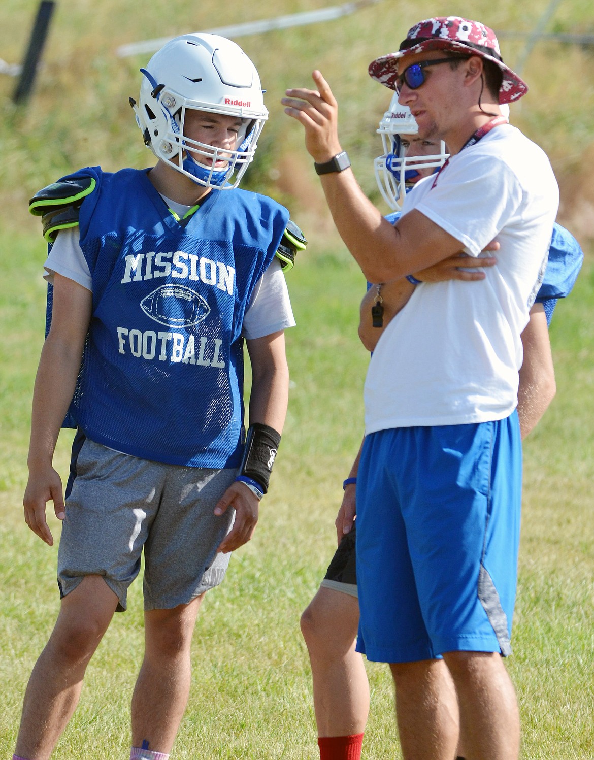 MISSION HIGH School football coach Tyler Murray (right) talks strategy with Isaac DuMontier (left) and Charlie Adams (back) during the Bulldogs' three-day camp at Mission High School. (Jason Blasco/Lake County Leader)