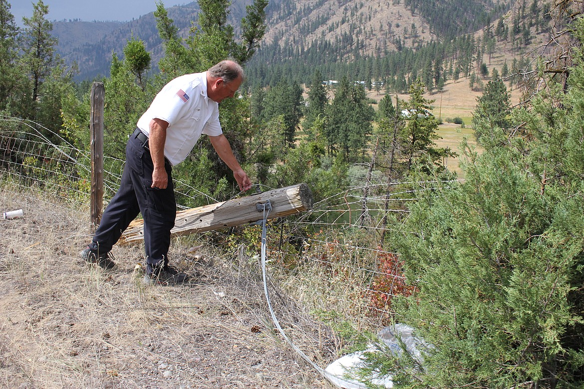 Superior Fire Chief Steve Temple examines the top of a power pole that snapped as a result of a cable being snagged by a semi-track on Interstate 90 west of Superior on July 24. (Kathleen Woodford/Mineral Independent).