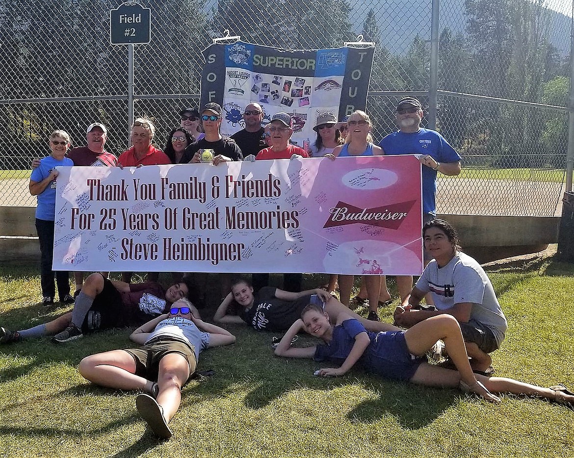 Players in the Superior Softball Tournament pose in front of a sign thanking Steve Heimbigner for 25 years of organizing the annual event. He is stepping down from that role this year. (Photo courtesy of Superior Softball)