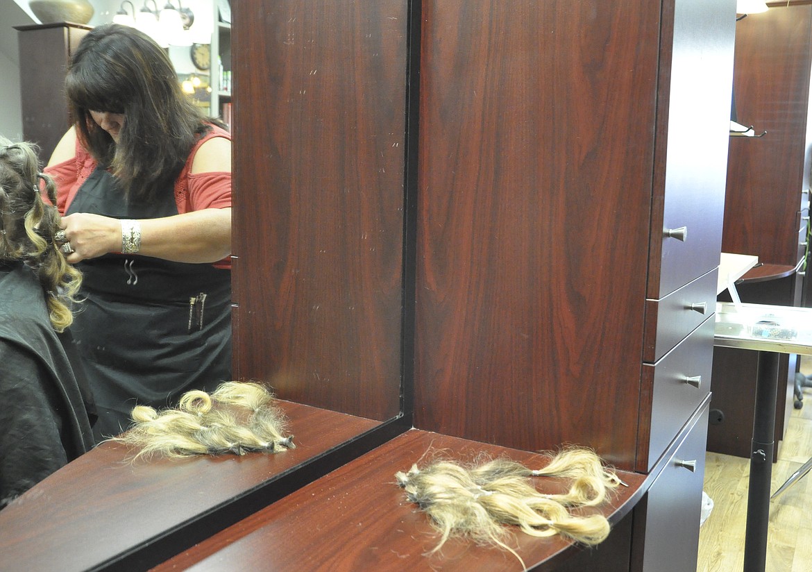 SECTION BY SECTION, cosmetologist Lisha Fitzpatrick of Mane Ideas Salonge in Polson cuts off hair that a narcotics detective with the Lake County Sheriff&#146;s Office grew for two years. (Ashley Fox/Lake County Leader)