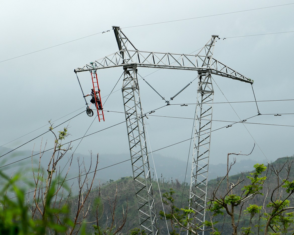 A Whitefish Energy contractor hangs from a ladder attached to a power line in the mountains of Puerto Rico to repair a transmission line segment. (Photo courtesy of Whitefish Energy)