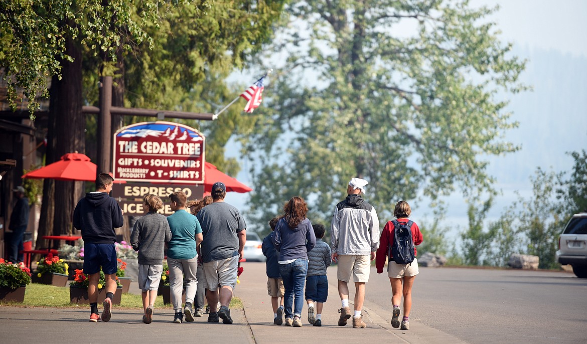 Two families, one from New York and the other from Virginia stroll through Apgar Village in Glacier National Park on Monday, August 13. They got a first hand view of the fires ramping up much more quickly than normal on Sunday night.(Brenda Ahearn/Daily Inter Lake)