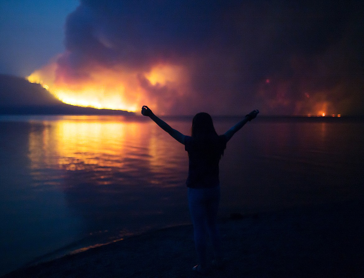 A girl poses for a photo in front of the Howe Ridge Fire Sunday night.