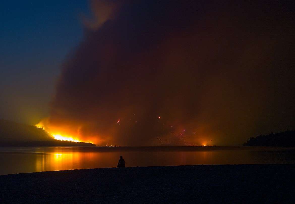 A person watches the Howe Ridge Fire Sunday from the shores of Lake McDonald in Glacier National Park.