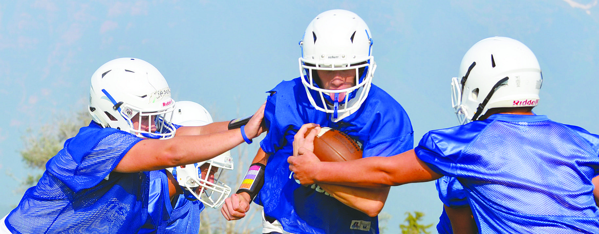 MISSION HIGH School Wacey McClure attempts to hold onto the ball while his teammates attempt to strip him of the fooball to create a fumbe during one of the work stations during the first official week of Montana High School Association practice Friday afternoon at Mission High School. (Jason Blasco/Lake County Leader)