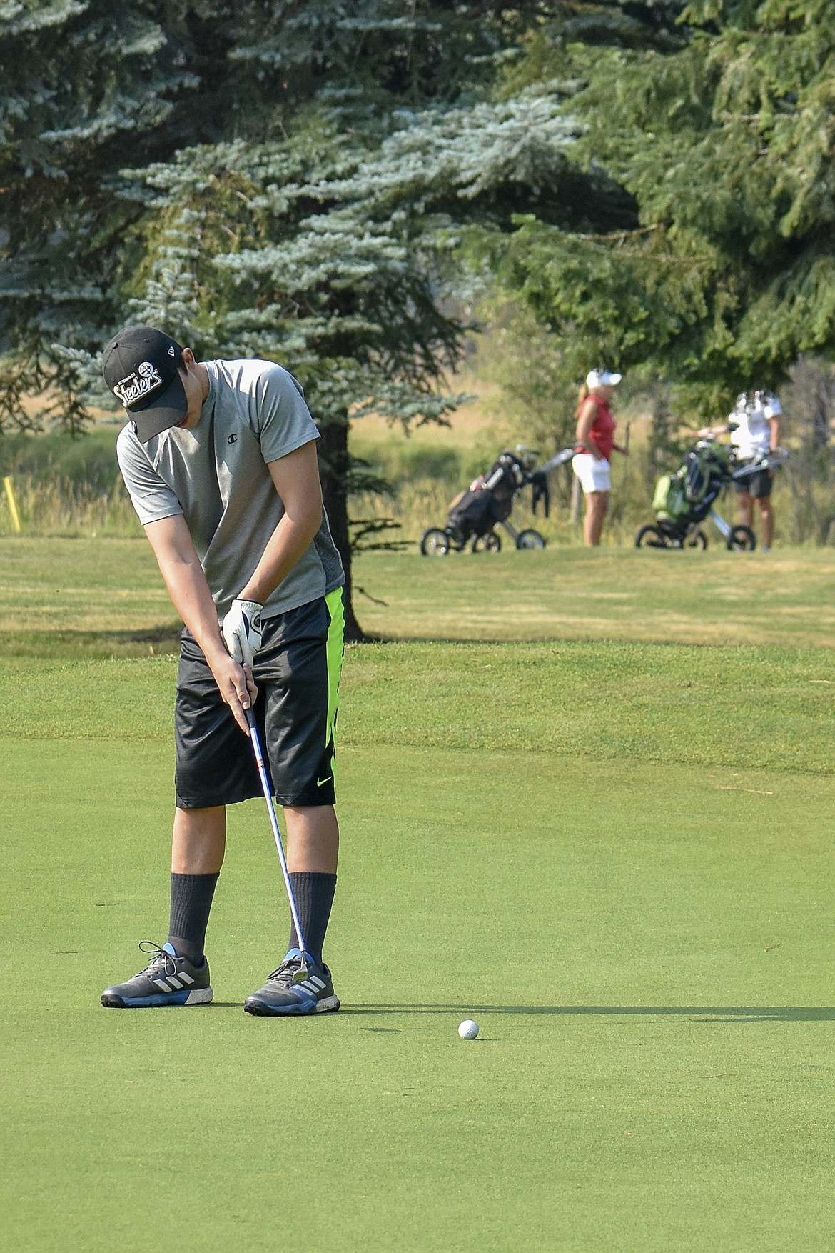 Junior Trey Thompson putts on the first hole at Cabinet View Golf Club Friday during the first morning practice for Logger golf. (Ben Kibbey/The Western News)