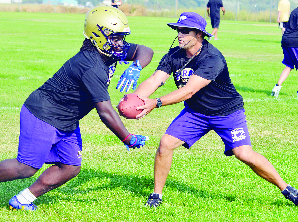 PIRATE ASSISTANT Coach Don Toth (left) hands off the ball to Esaie Kinsey (right) during the first official practice of the Polson Pirates&#146; 2018 season at Polson High School. (Jason Blasco/Lake County Leader)