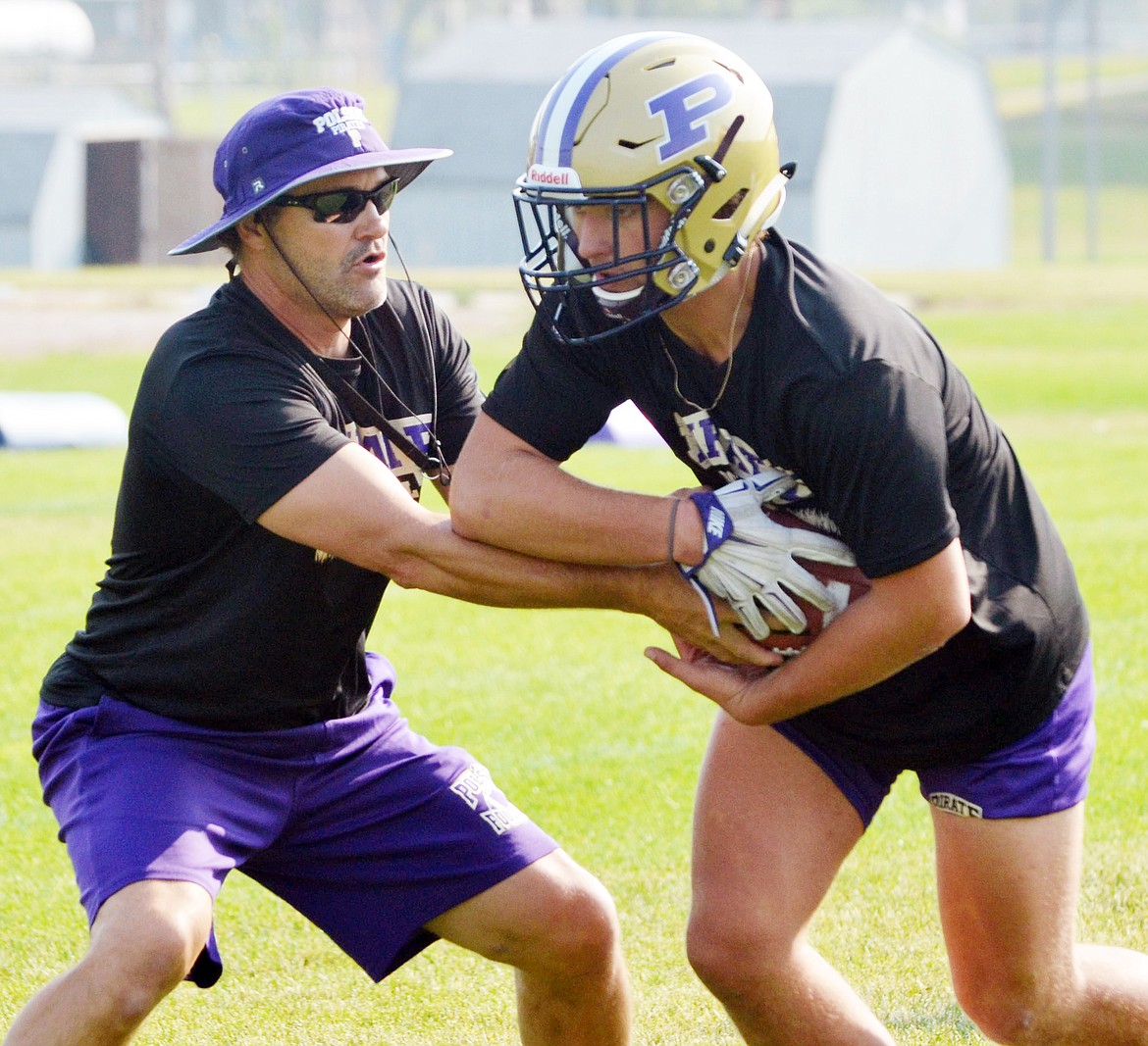 POLSON RUNNING BACK/Linebacker Hunter Fritsch (right) takes the handoff from Pirates&#146; assistant coach Don Toth (left) during Polson&#146;s first official day of MHSA-sanctioned practice Friday morning at Polson High School. (Jason Blasco/Lake County Leader)