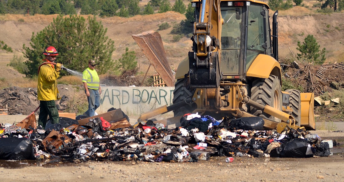 Kelly Slusher stays on the hose to ensure a trash fire is completely out. (Erin Jusseaume/Clark Fork Valley Press)