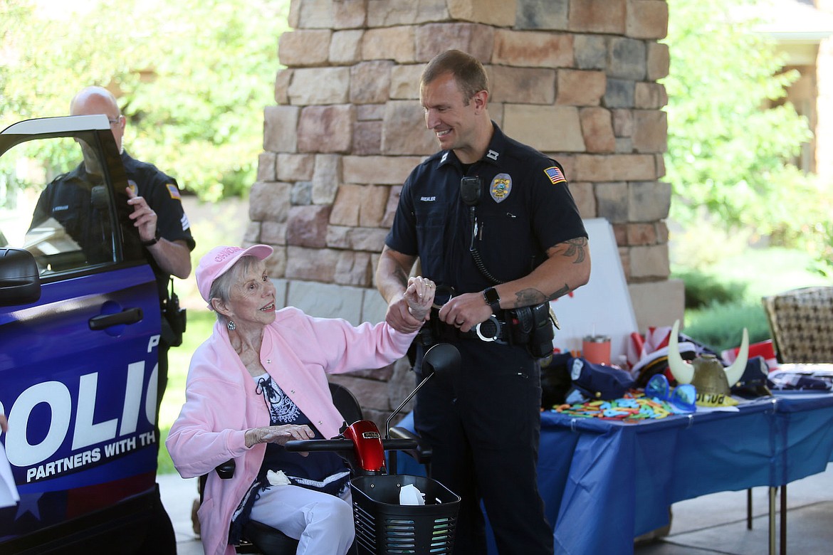 Capt. Jason Mealer of the Post Falls Police Department jokingly handcuffs Garden Plaza resident Dorothy Ertel for speeding at a Holidays and Heroes photo shoot July 20.