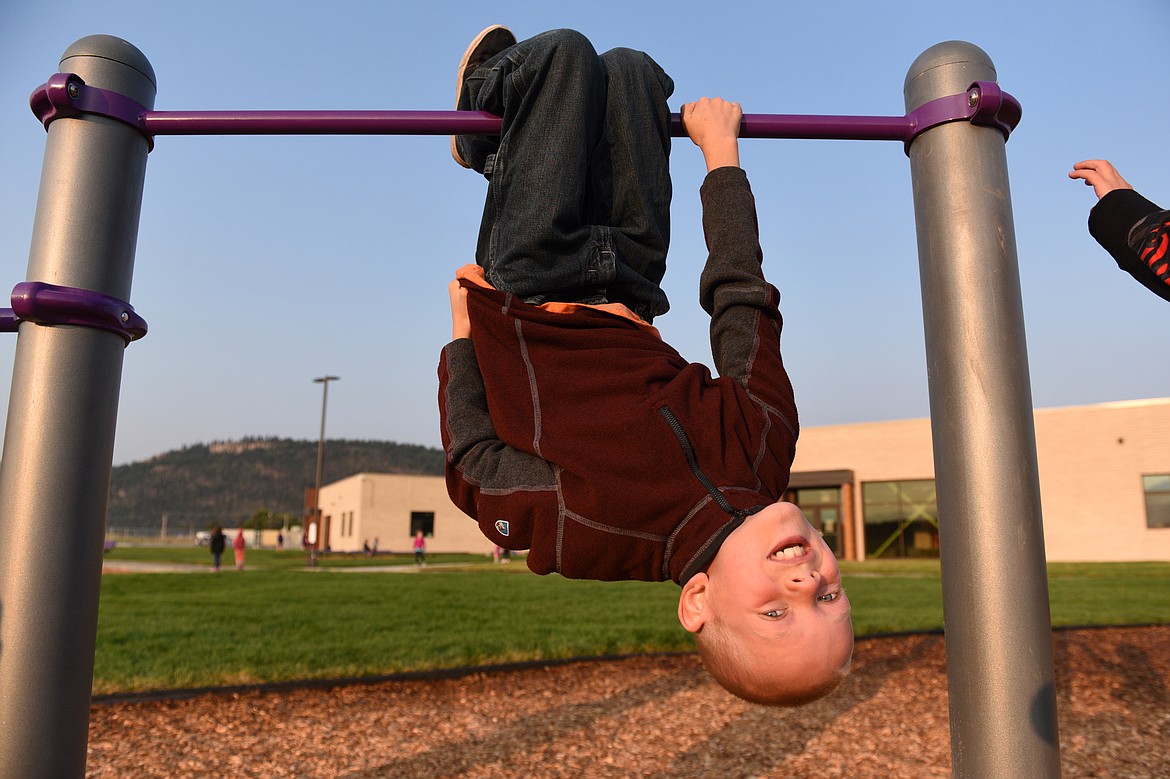 Third-grader Conor Rogers hangs upside down on the playground before the first day of school at Rankin Elementary School in Kalispell on Wednesday. (Casey Kreider/Daily Inter Lake)