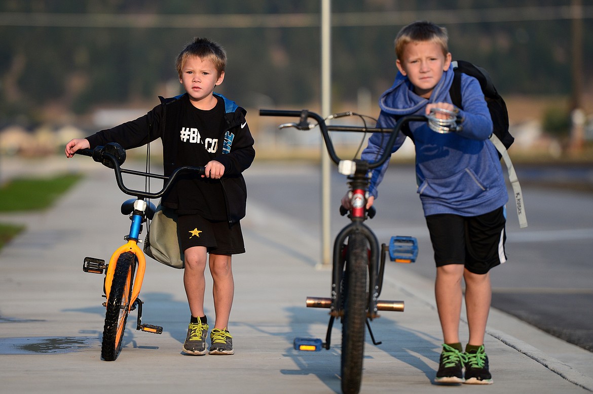 First-grader Kyler Kubai, left, and his brother Kayvis, a third-grader, walk their bikes to the rack before the first day of school at Rankin Elementary School in Kalispell on Wednesday.