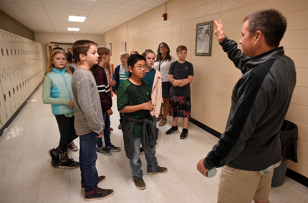 Rich Evans, who teaches wood shop, construction and STEM classes at Kalispell Middle School waves to a group of passing sixth graders as they tour the building on Wednesday morning, August 29. In the foreground are Curtis Dougherty, in gray, and Vincent Lam, in green. The new sixth graders had the school to themselves for the day to get adjusted to their new home without the pressure of finding their way with the entire student body on site.(Brenda Ahearn/Daily Inter Lake)