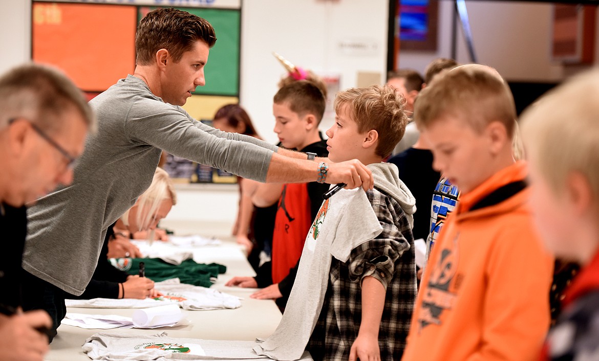 Eighth grade health teacher Noah Couser holds a tee shirt up to new sixth grader Dante Ramsdell as he is outfitted for his gym class on Wednesday, August 29, at Kalispell Middle School. The first day of school at KMS is now Sixth Grade Day, a chance for the youngest students to come in and find their way around before the entire student body returns.(Brenda Ahearn/Daily Inter Lake)