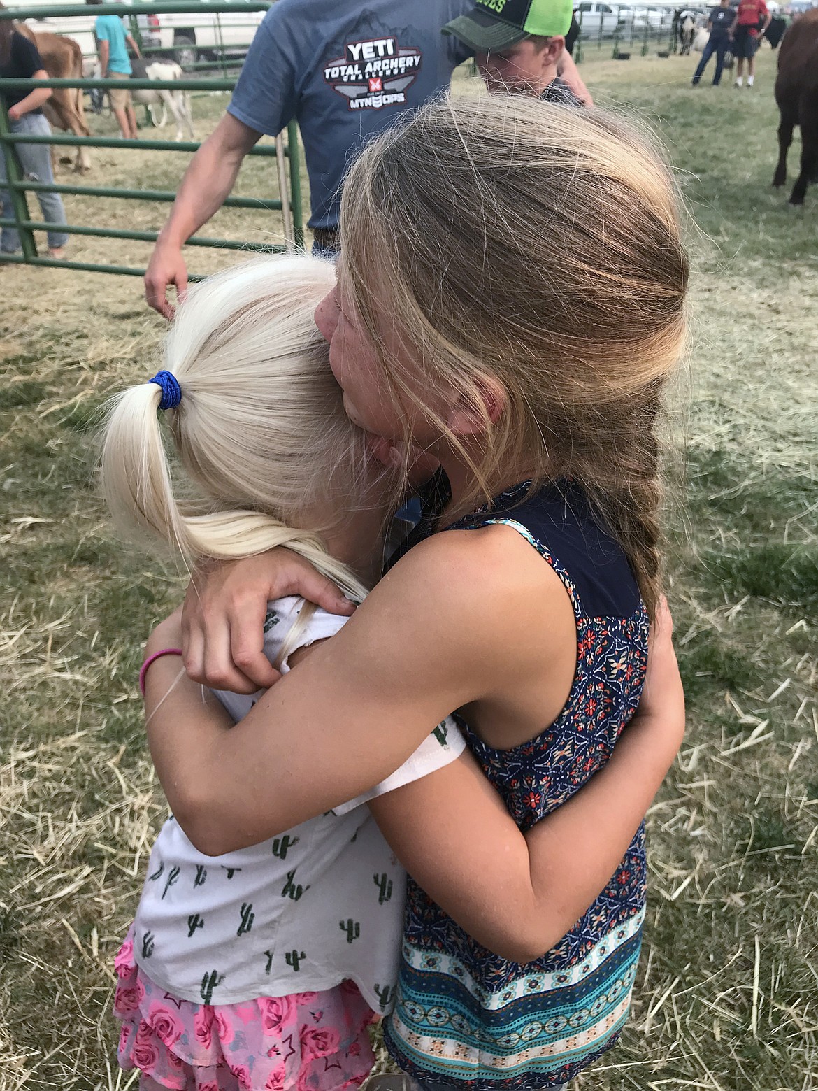 Ione Plummer, 10, and her sister Sadie, 6, embrace each other after Ione&#146;s and brother, Sam&#146;s market beef are driven away to Vandevanter Meats on Aug. 19 at the Flathead County Fairgrounds. (Hilary Matheson/Daily Inter Lake)