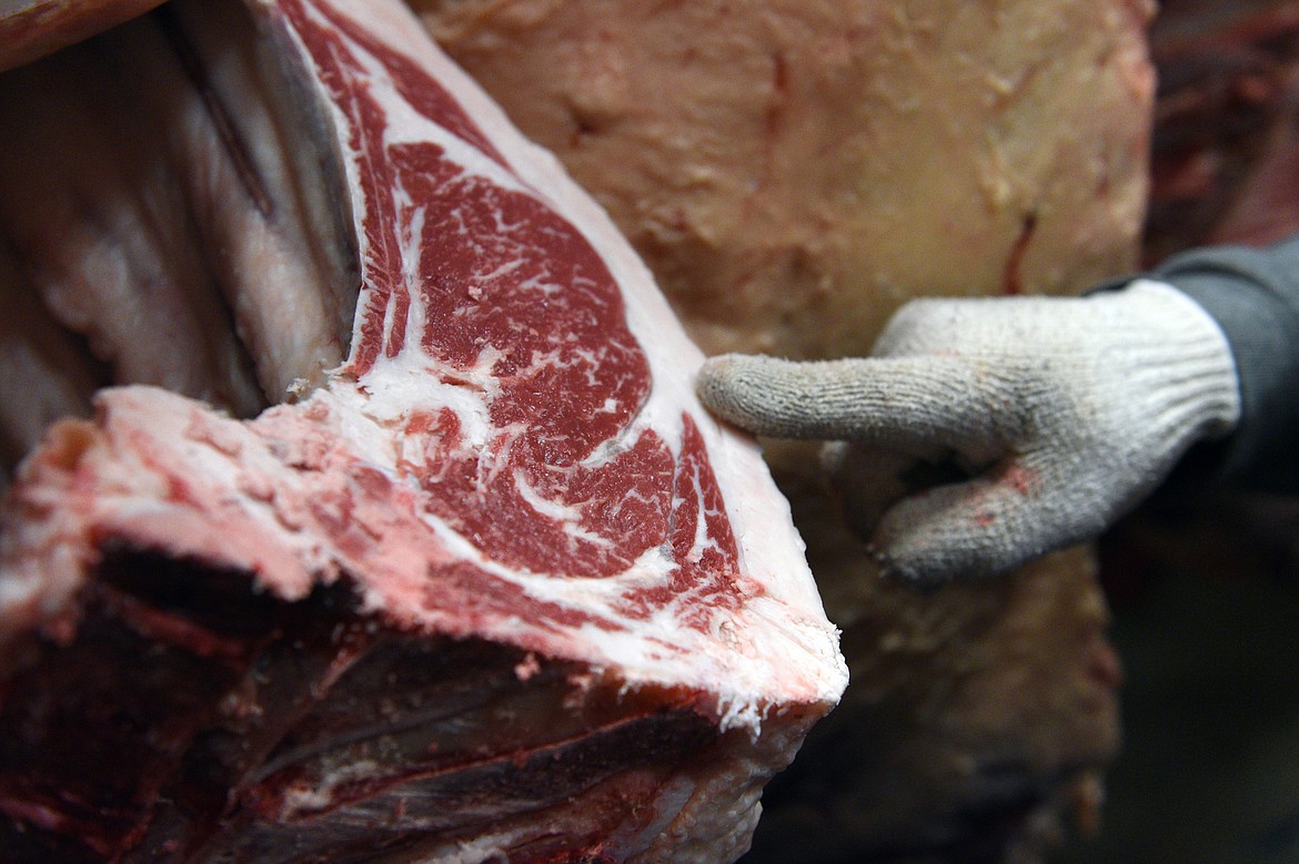 Ron Vandevanter, of Vandevanter Meats, shows the Plummers a ribeye cut of beef inside the cooler in Columbia Falls on Wednesday, Aug. 22. (Casey Kreider/Daily Inter Lake)