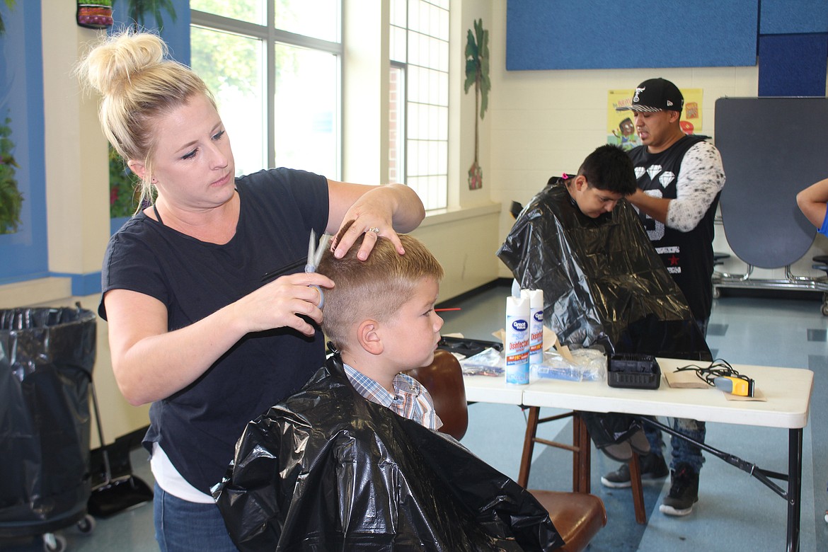 Cheryl Schweizer/Columbia Basin HeraldVolunteers gave kids a back-to-school haircut at the first 'Back to School' distribution in Warden Friday. Kids also received school supplies.