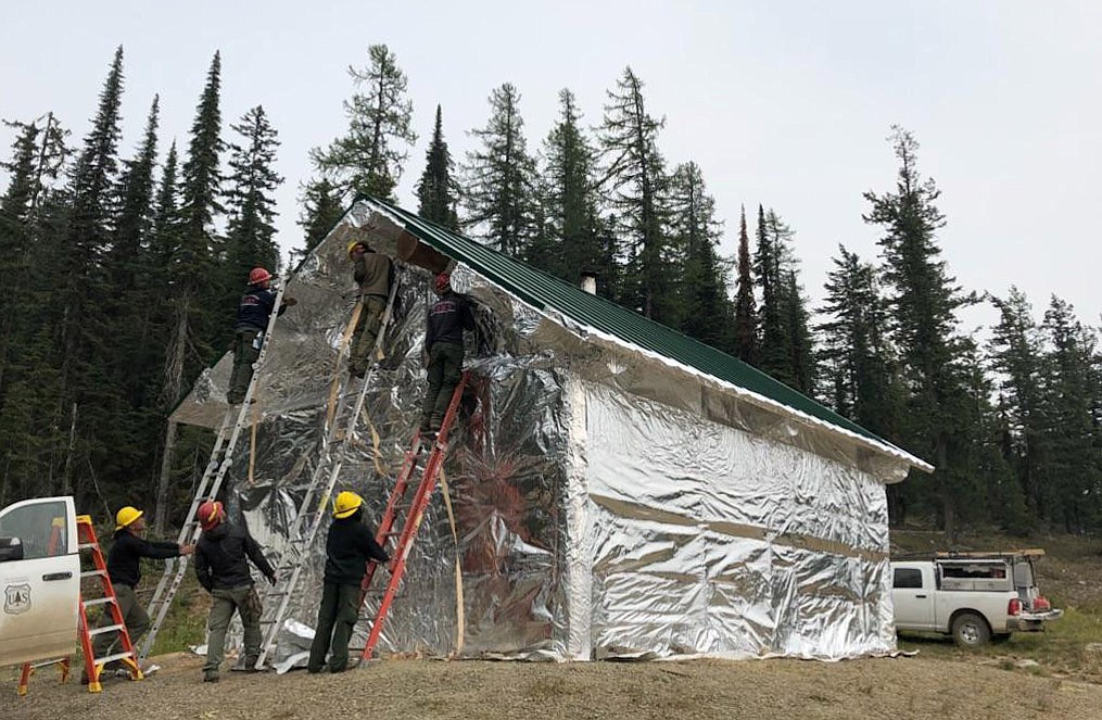 A U.S. Forest Service crew wraps a warming hut in the vicinity of the Gold Hill fire in a photo provided Monday. (Courtesy U.S. Forest Service/Kootenai National Forest)