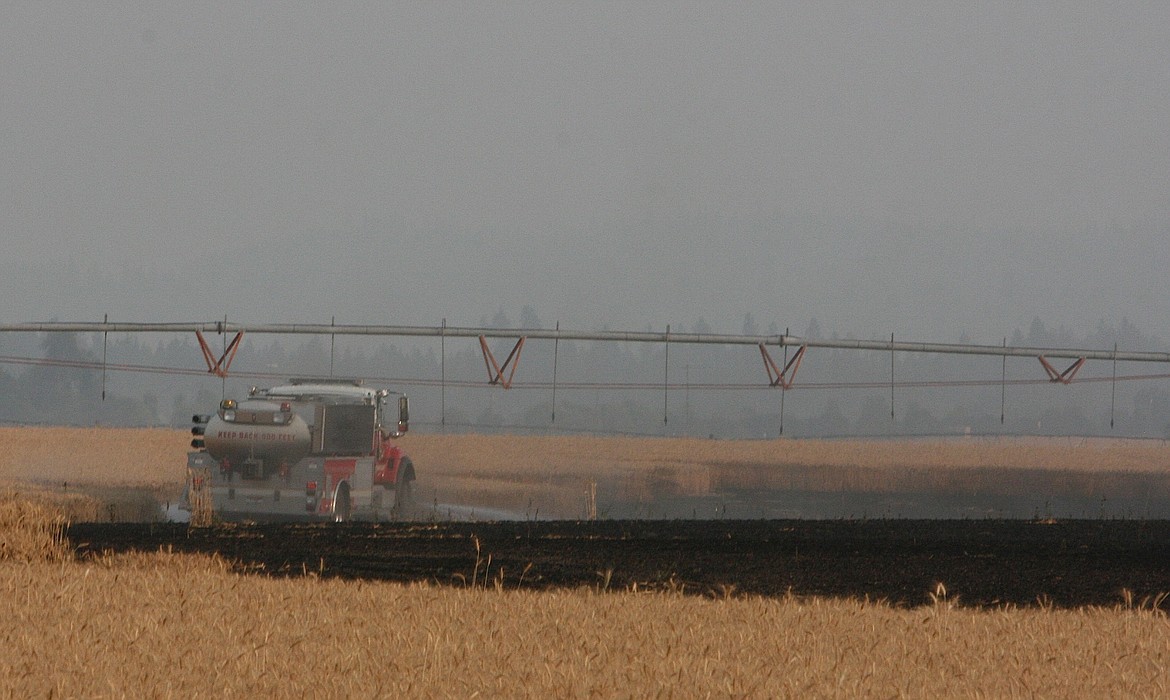 Water is applied to the perimeter of the burned area of the wheat field fire north of Post Falls on Tuesday night. (BRIAN WALKER/Press)