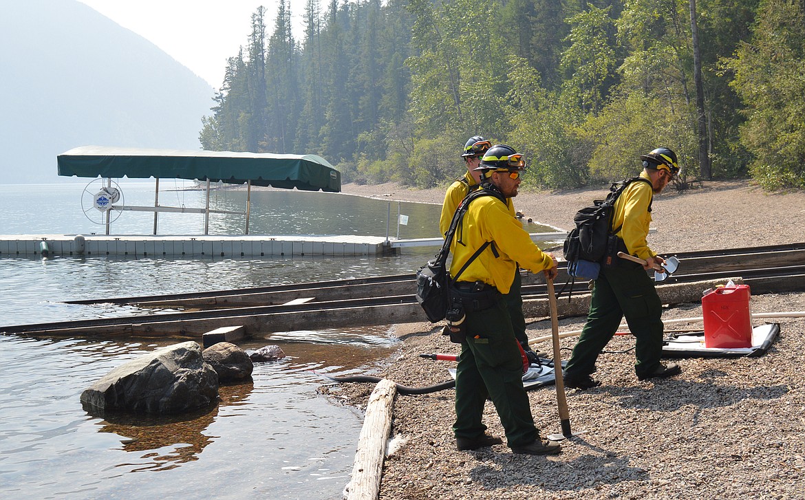 Type 1 team fierefighters pump water from Lake McDonald into sprinkler systems set up to wet a historic boathouse and surrounding property at Fish Creek Campground.