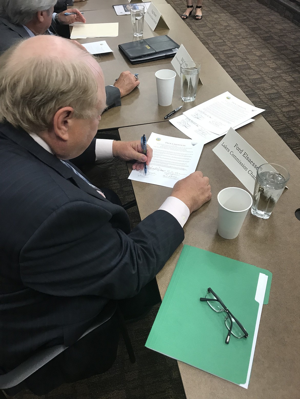 (Photo by KEITH KINNAIRD)
Idaho Lakes Commission Chairman Ford Elsaesser puts his signature on the settlement agreement between the state and the Bonneville Power Administration on Thursday.