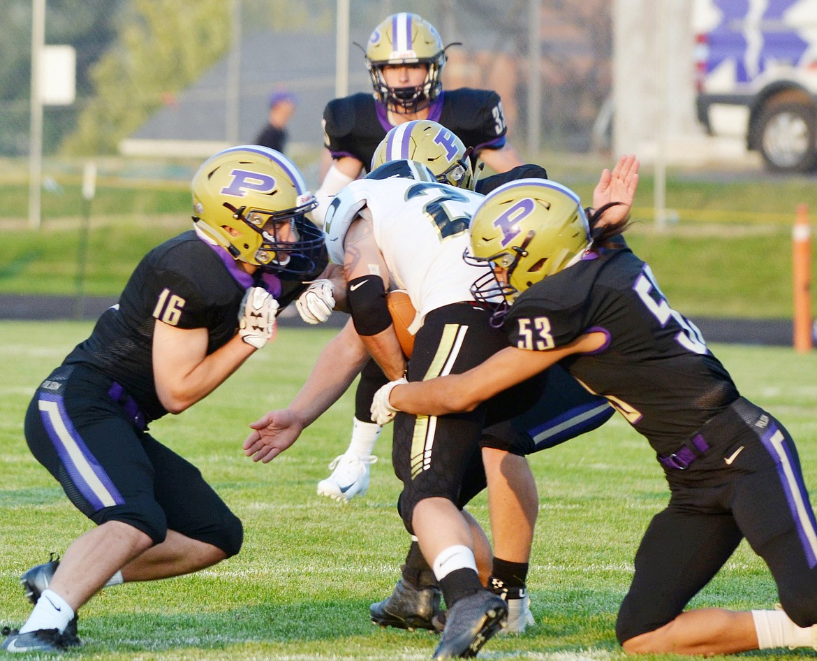 POLSON HIGH School defensive players Caleb Pierre (53), Kaleb Unger (16), and Corbyn Lund (33) all swarm to the Stevi wide out during the first half of the Pirates season-opening game Friday night at Polson High School. (Jason Blasco/Lake County Leader)