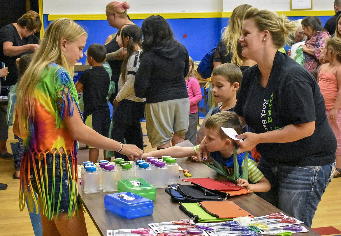 Ashley Freese helps Hayden Caudill pick out a water bottle as he picks up school supplies along with older brother Tristin and mother Brittany during the Student Stand Down at Asa Wood Aug. 20. Freese said that her mother&#146;s store, Libby&#146;s Closet, was helping to raise money for the Stand Down when Ashley heard they needed help the day of, so she volunteered. (Photos by Ben Kibbey/The Western News)