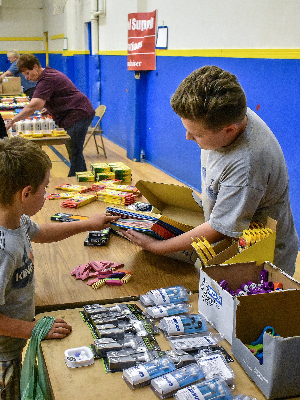 Jaden Ueland helps Ghavin Amos pick out a folder during the Student Stand Down at Asa Wood Aug. 20. Ueland &#151; who wore a smile on his face throughout &#151; said that his mom was volunteering with the Stand Down and he wanted to help, and was happy he did. (Ben Kibbey/The Western News)