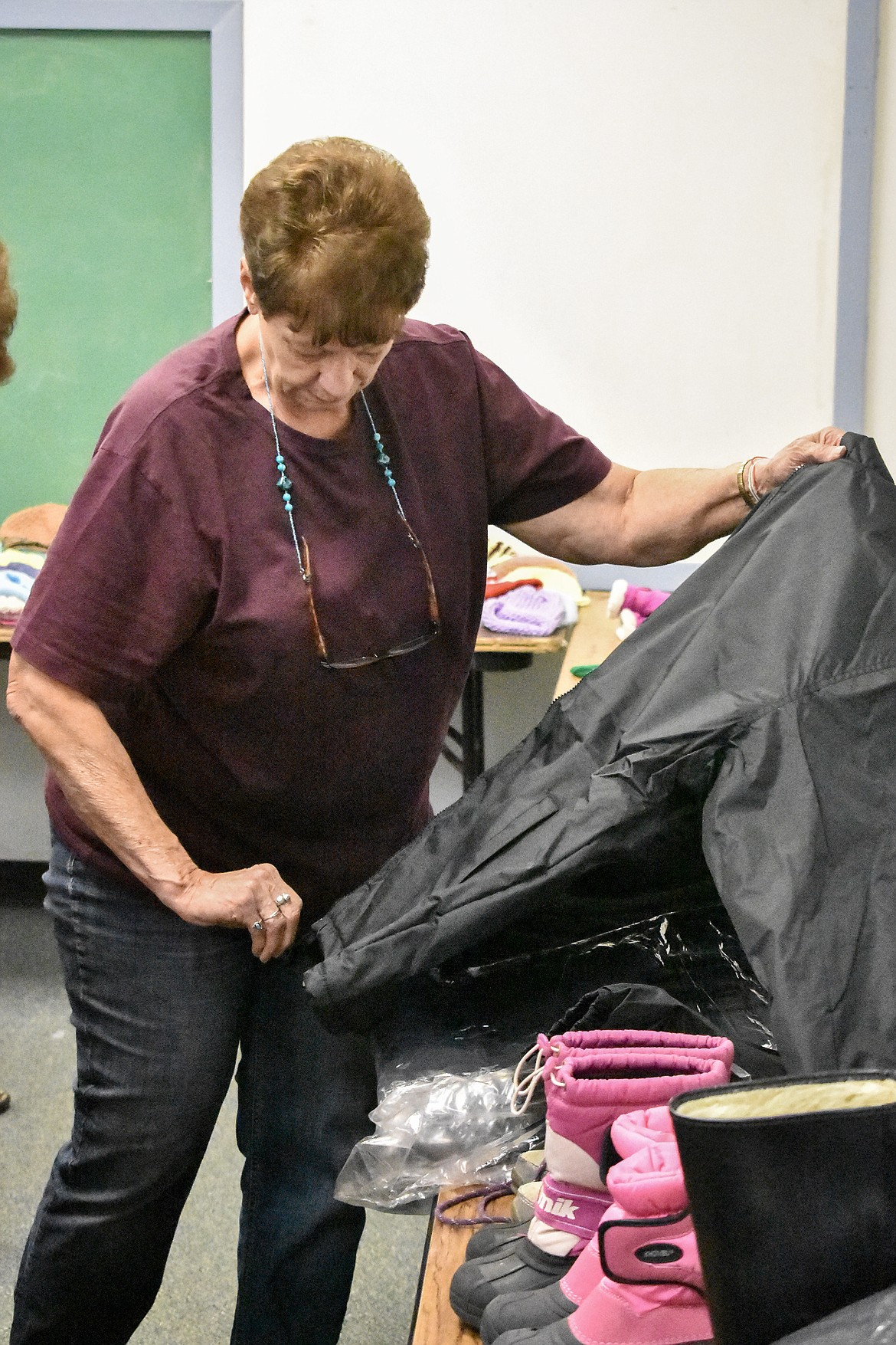 Connie Thomson, who came to volunteer for the Student Stand Down Aug. 20, looks at a coat in the Koats for Kids room before the Stand Down gets started. Kooteani Kiwanis president Pam Peppenger said Koats for Kids gave away around 200 pieces of winter wear during the Stand Down, including 100 coats. 
(Ben Kibbey/The Western News)