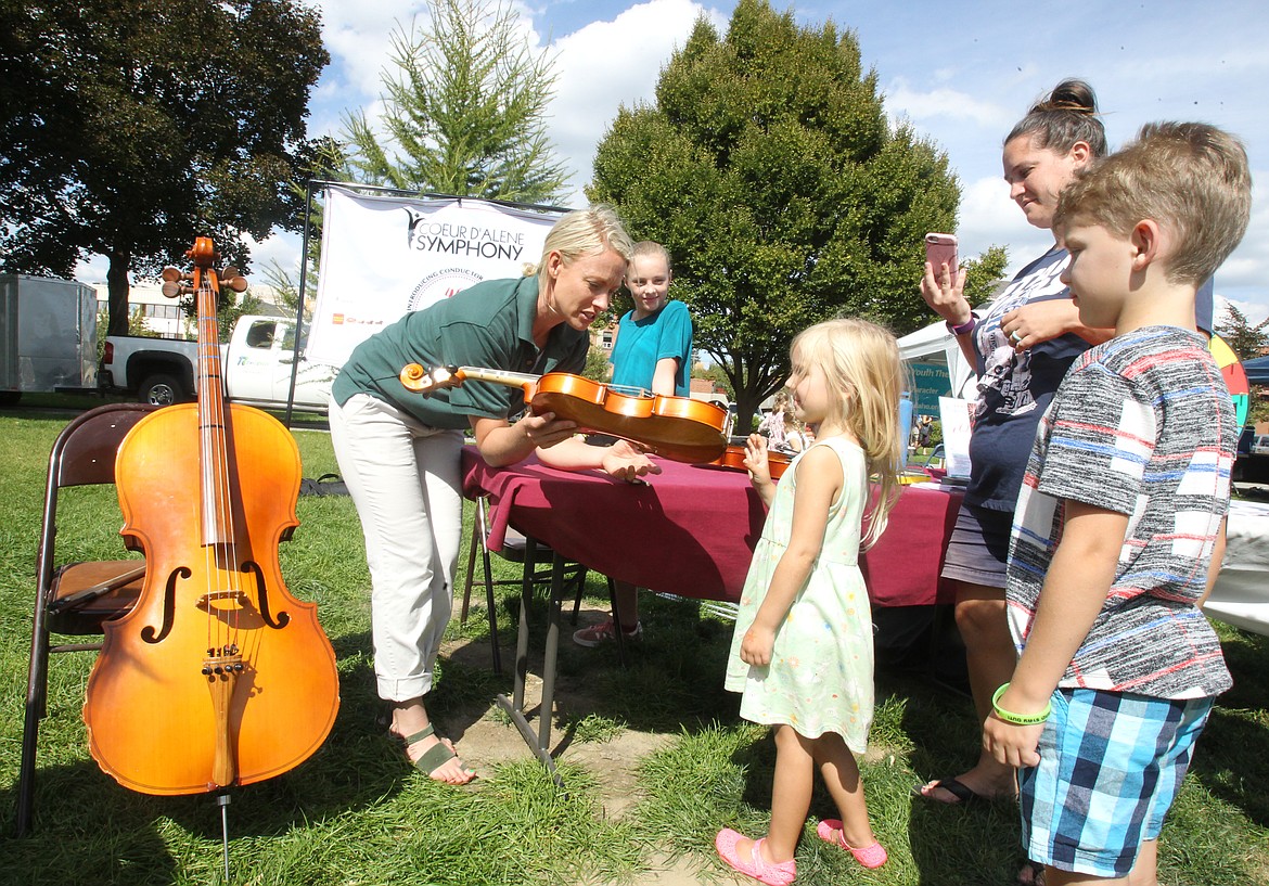 Photos by DEVIN WEEKS/Press
Coeur d&#146;Alene Symphony second violinist and board member Sarah Zastrow encourages 5-year-old Olivia Clark of Post Falls to give the violin a try Saturday afternoon during the first COEURfest in McEuen Park. Olivia&#146;s big brother, Jeremiah, 9, and mom, Lauren, right, also enjoyed the hands-on experience.