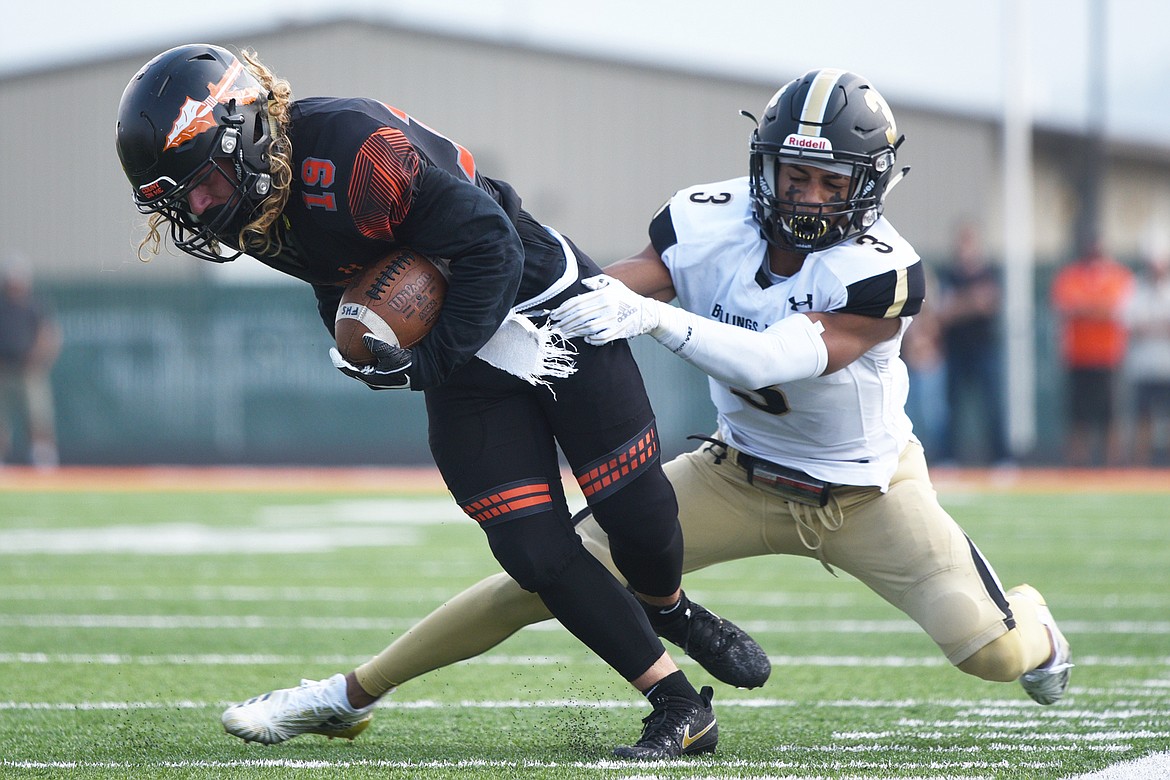 Flathead wide receiver Kaden Wills (19) tries to break a tackle by Billings West's Jesse Owen (3) at Legends Stadium on Friday. (Casey Kreider/Daily Inter Lake)