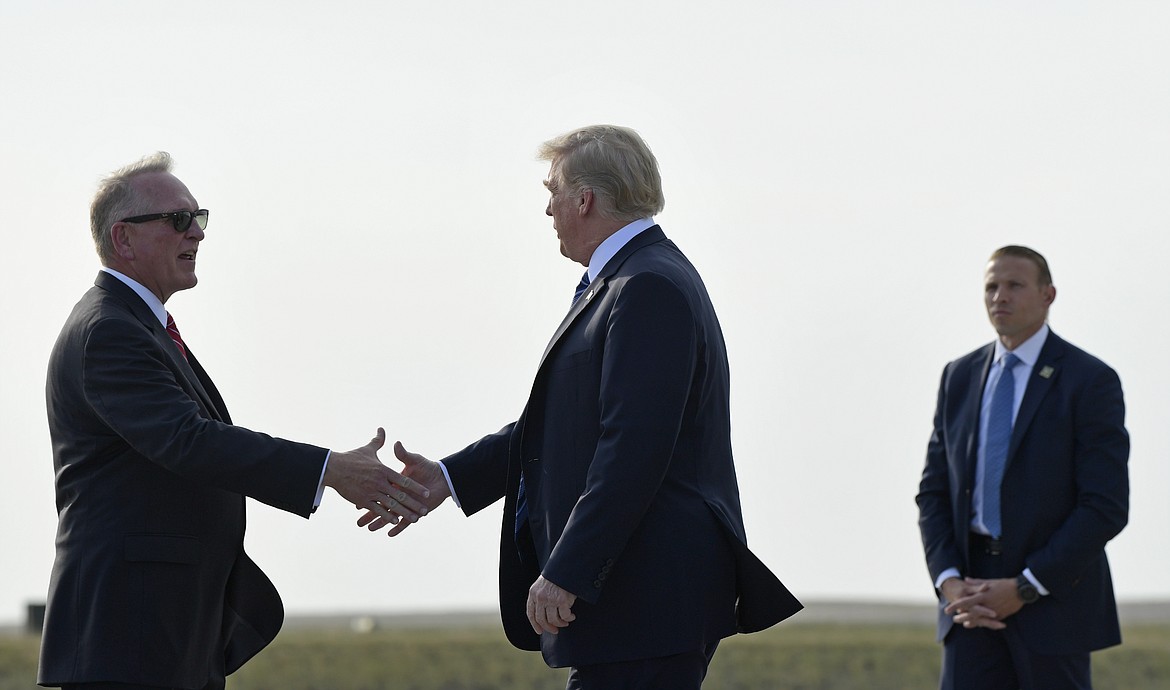 President Donald Trump, center, shakes hands with Montana Attorney General Tim Fox, left, after arriving at Billings Logan International Airport in Billings, Mont., Thursday, Sept. 6, 2018. Trump is in Montana for a rally. (AP Photo/Susan Walsh)