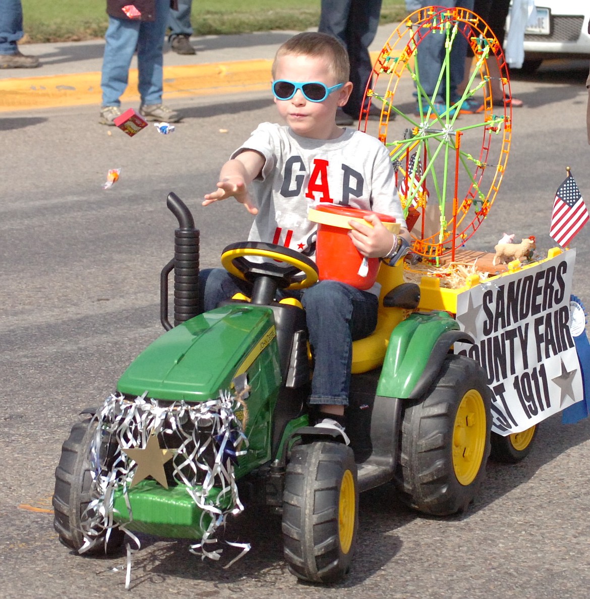 Six-year-old Decker Bates of Plains throws candy during the Sanders County Fair Parade on Saturday. It was Decker's fourth such parade on his electric tractor. (Joe Sova/Clark Fork Valley Press)