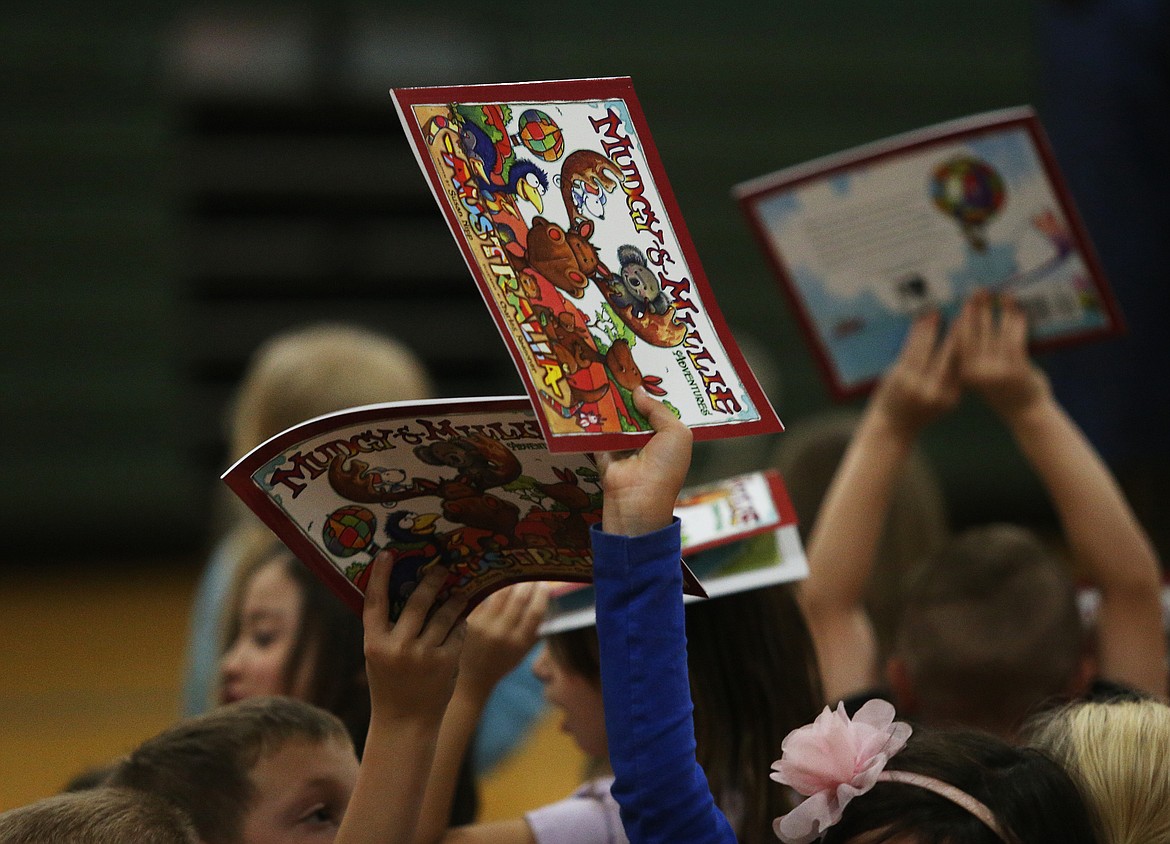 LOREN BENOIT/Press
A first-grader raises her free gifted Mudgy and Millie book high in the air Tuesday at Atlas Elementary School.