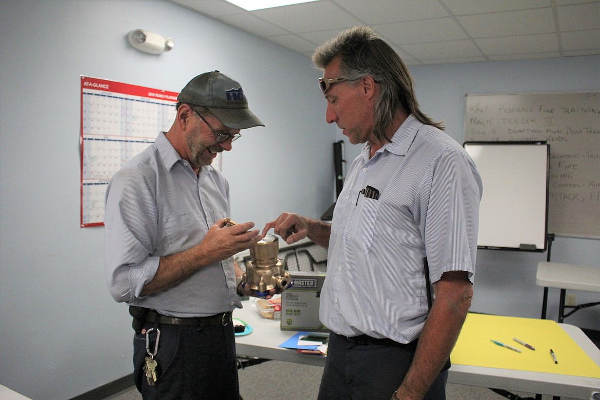 Roger Wasley, left, accepts a gold-painted water meter as a &#147;going away present&#148; from Rodney Goins, right. Wasley is retiring as Superior&#146;s Public Works Supervisor and will be replaced by Goins.