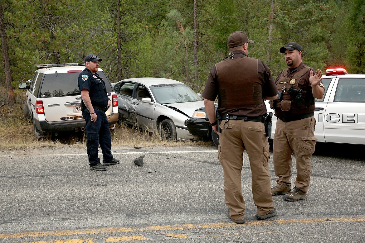Libby Police Officer Chris Pape, left, and Lincoln County Sheriff's deputies John Davis, center, and Brandon Holzer confer at a crash site near mile marker 4 on Pipe Creek Road Monday. The incident stemmed from a Libby man's refusal to pull over for Holzer in downtown Libby. (John Blodgett/The Western News)