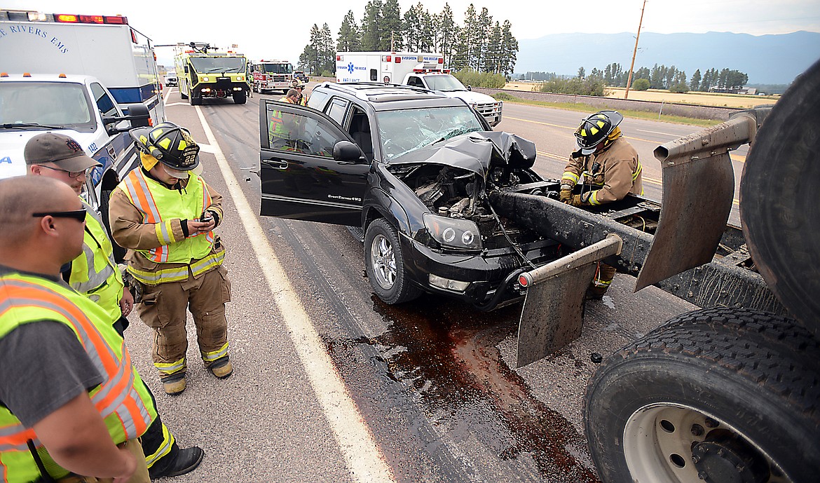 Firefighters from Evergreen work the scene of a collision between an SUV and a logging truck at the light for Glacier Park International Airport on Friday evening, April 14, north of Kalispell. (Brenda Ahearn/Daily Inter Lake)