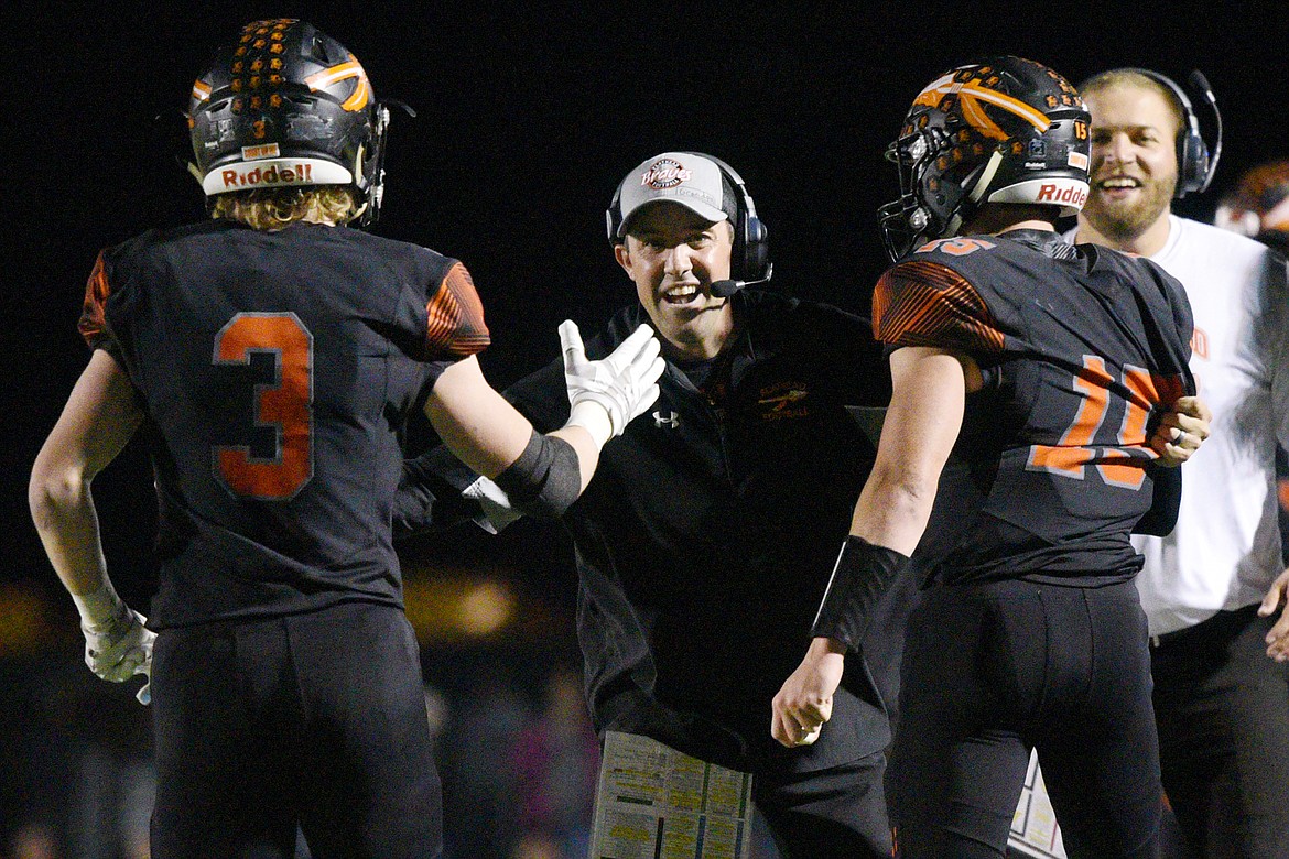 Flathead head coach Kyle Samson congratulates Chance Sheldon-Allen (3) and quarterback Jaden MacNeil in the third quarter of a crosstown matchup with Glacier at Legends Stadium on Friday. Sheldon-Allen had a key interception that would set up a 36-yard touchdown run by MacNeil late in the third quarter. (Casey Kreider/Daily Inter Lake)