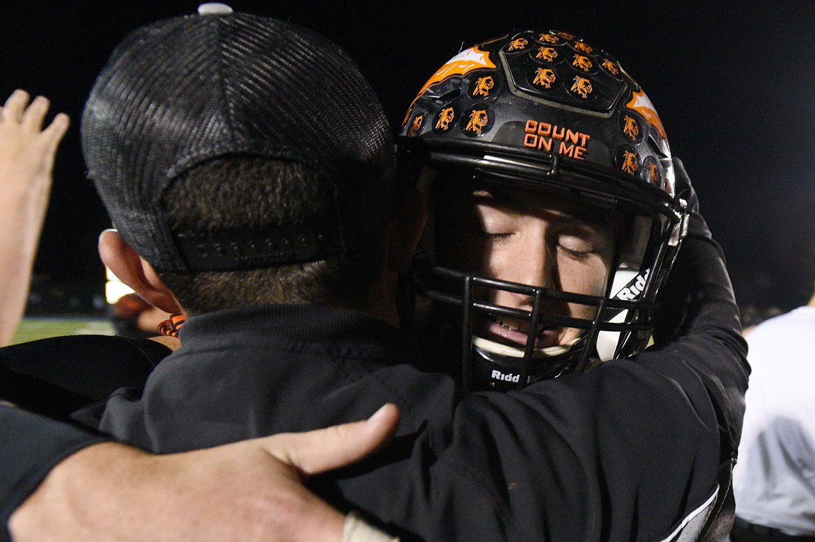 Flathead quarterback Jaden MacNeil gets a hug from head coach Kyle Samson after the Braves 28-27 crosstown victory over Glacier at Legends Stadium on Friday. (Casey Kreider/Daily Inter Lake)