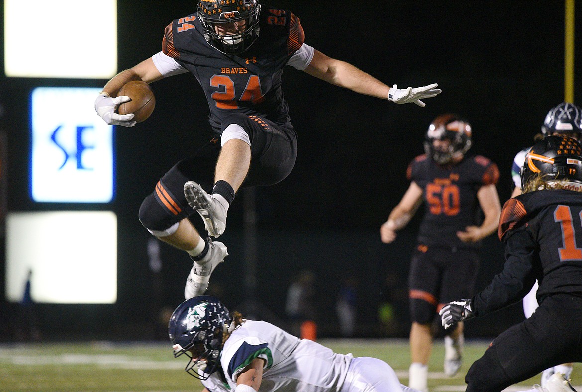 Flathead running back Blake Counts (24) hurdles Glacier defensive back Danny Anderson (3) on a second half run at Legends Stadium on Friday. (Casey Kreider/Daily Inter Lake)