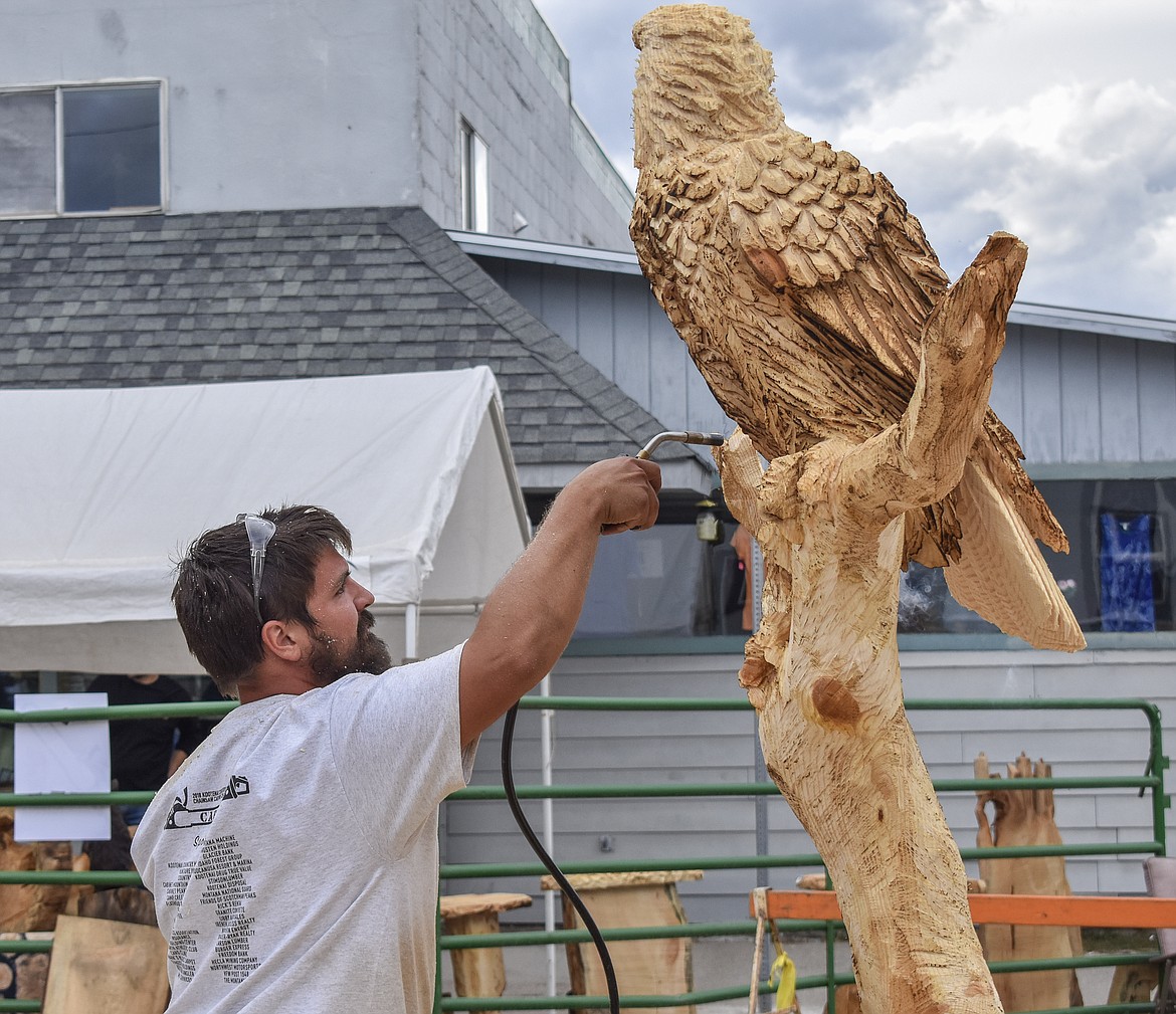 Competition winner Joe Dussia from the U.S. uses a propane torch to color his winning piece during the Kootenai Country Montana Chainsaw Carving Championship on Saturday. (Ben Kibbey/The Western News)