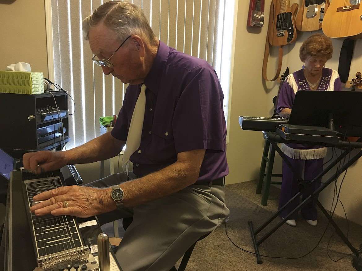 Gil Prier plays a steel guitar while wife Erma plays the keyboard in a music room of their Columbia Falls Home. (Ashley Fox/Lake County Leader)