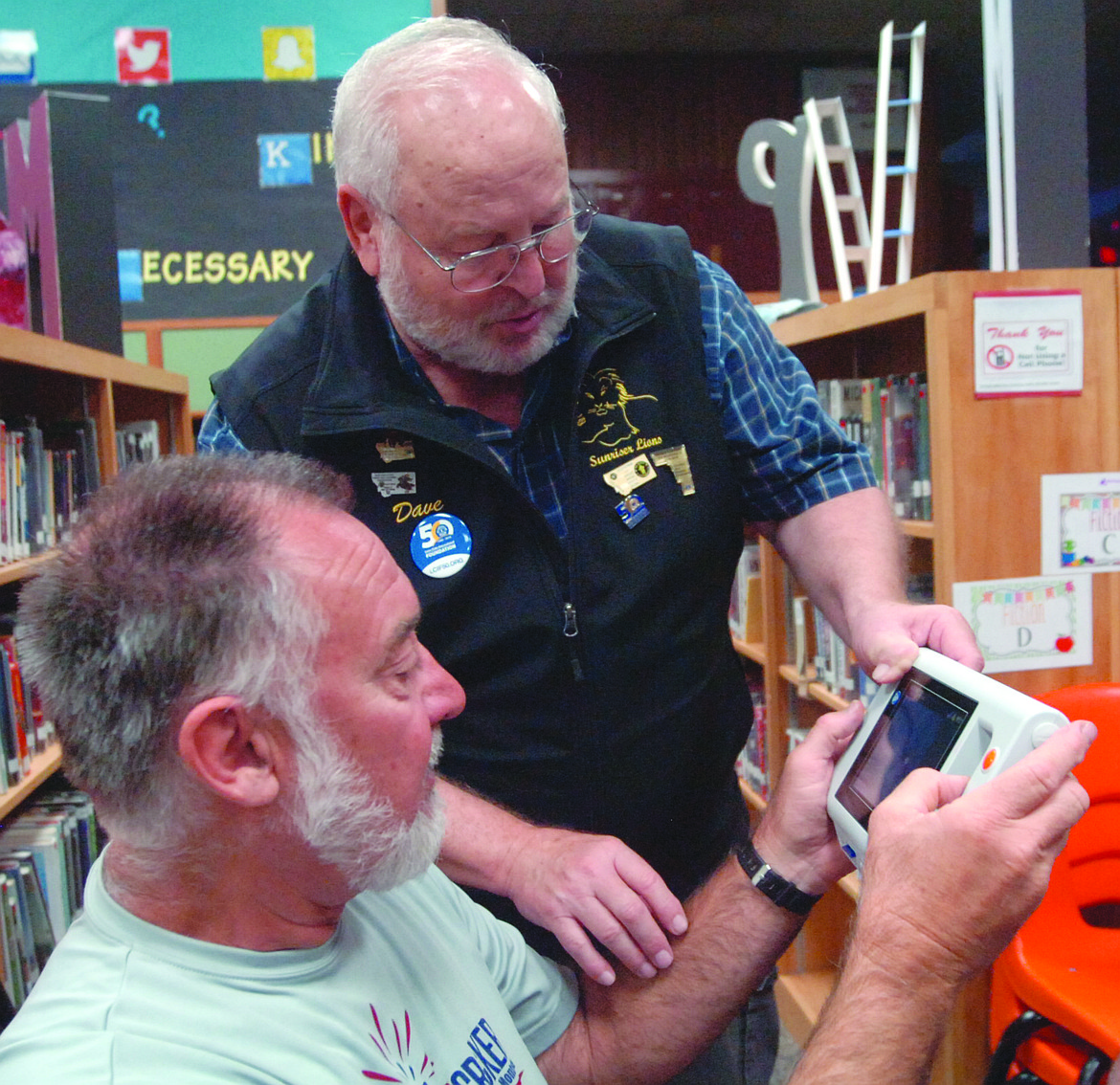 Dave Falcon of the Kalispell Lions Club shows Plains Lions Club Treasurer Marvin Tanner how to use the new plusoptix machine. The portable unit will be used to provide vision screening for students in Sanders County schools. (Joe Sova photos/Clark Fork Valley Press)
