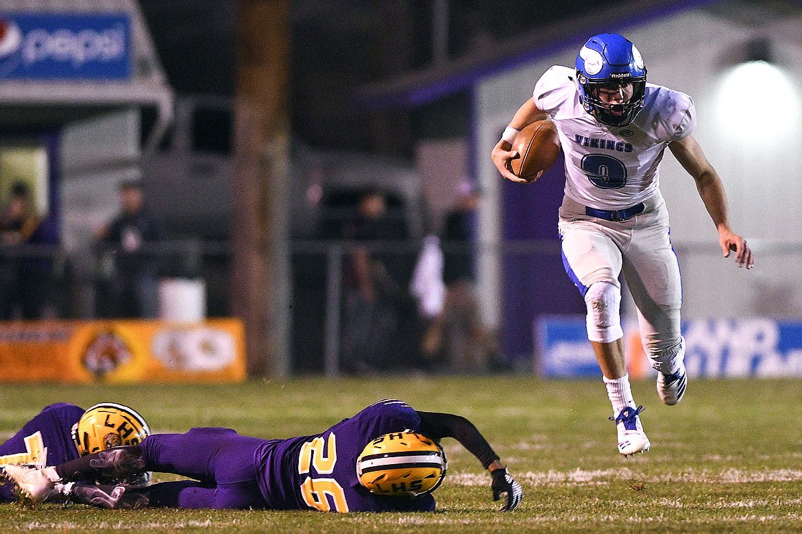 Coeur d'Alene quarterback Dietrich Edwards runs past tackle attempts by Lewiston's Tristan Thompson and Isaiah Walker (26) during the second quarter of an Inland Empire League game on Friday night at Bengal Field in Lewiston.