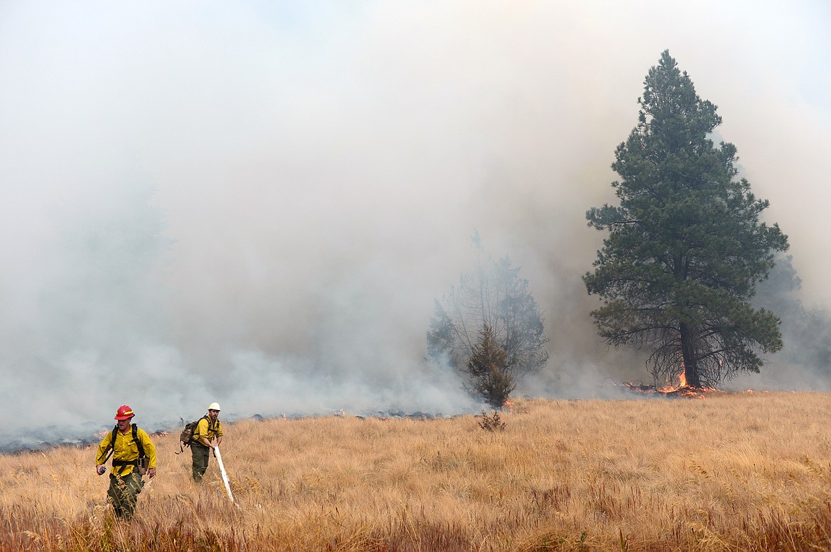 Forest Service firefighters at the scene of a fire in a field off Foys Lake Road in Kalispell on Tuesday. (Casey Kreider/Daily Inter Lake)