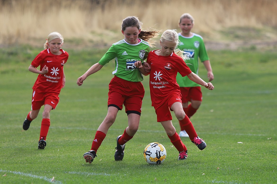 Photo by MIKE SCHMIDT
Olivia Smith (center, red shirt) of the FC Thorns North &#146;09 Girls Yellow team battles for the ball as teammate Ashley Yates (red shirt at left) looks on during a match vs. Spokane Sounders Valley.