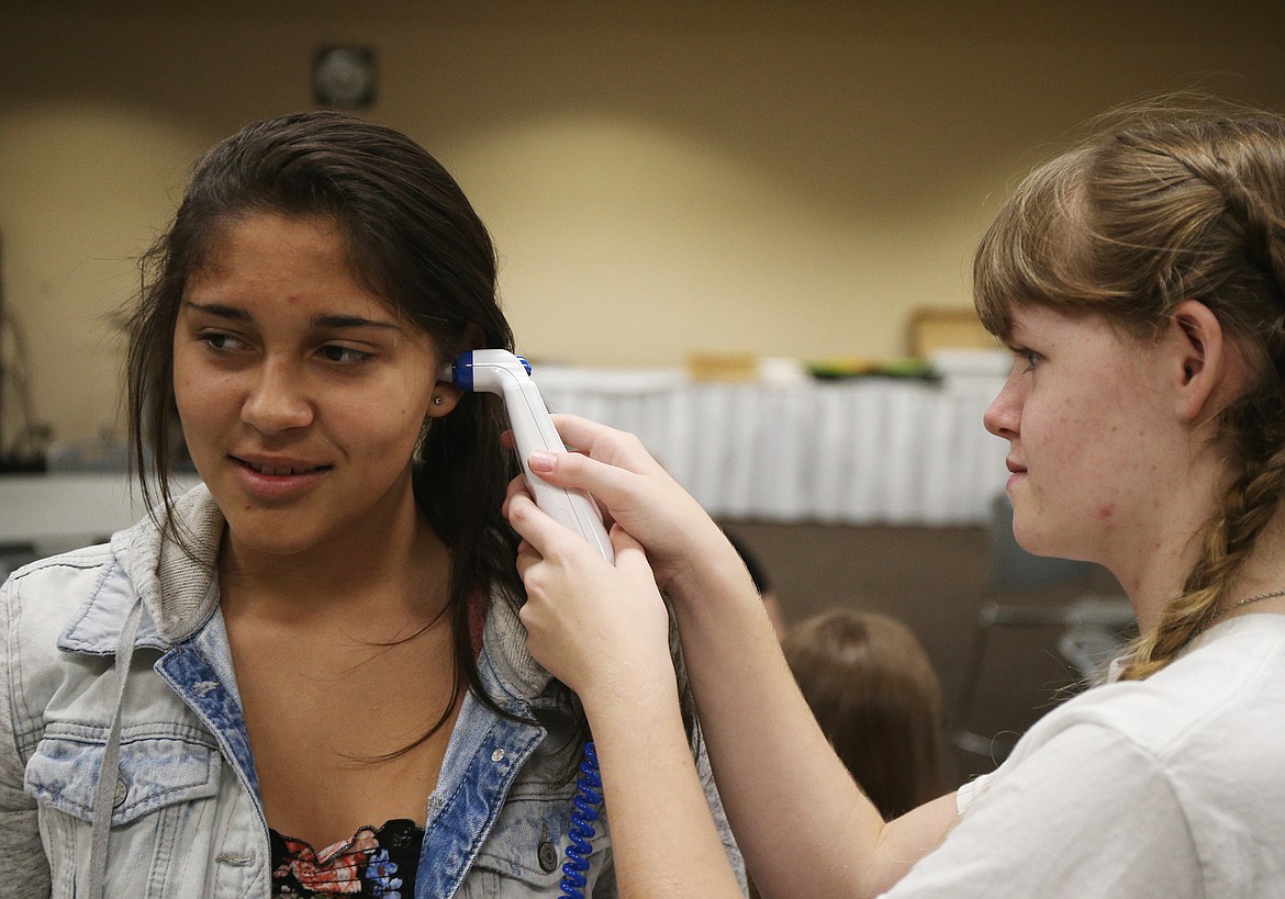 Lake City High School sophomore Alyssa Fenton, right, uses an ear thermometer to measure Kacilynn Uecker&#146;s body temperature Tuesday afternoon at University of Idaho&#146;s 10th annual Women in Math and Science event at North Idaho College. (LOREN BENOIT/Press)